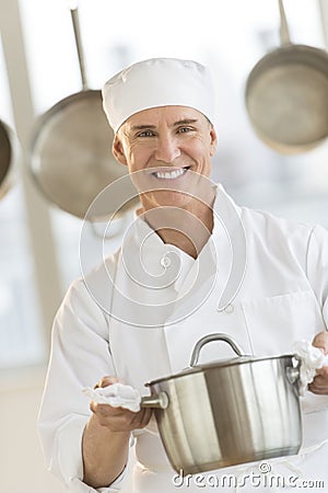 Happy Chef Holding Utensil In Commercial Kitchen Stock Photo
