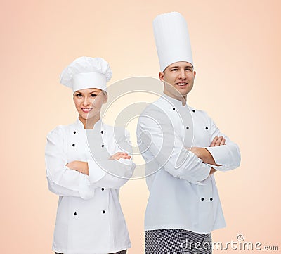 Happy chefs or cooks couple over beige background Stock Photo