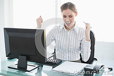 Happy chic businesswoman sitting at her desk in front of her computer Stock Photo