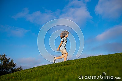 Happy child boy runs around the green field on blue sky, emotional walk on nature and happiness. Cute little boy having Stock Photo