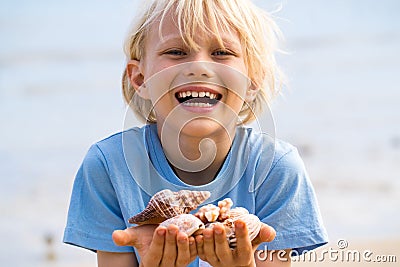 Happy child with collection of shells at beach Stock Photo