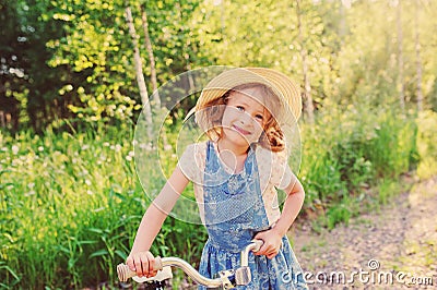 Happy child girl with bicycle on summer sunny road Stock Photo