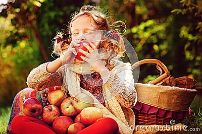 Happy child girl eating apples in autumn garden Stock Photo