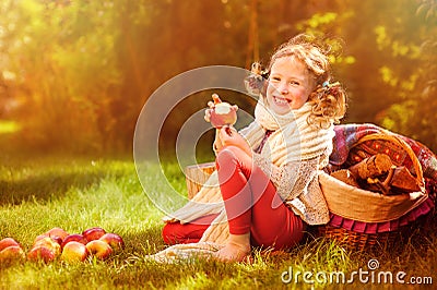 Happy child girl eating apples in autumn sunny garden Stock Photo