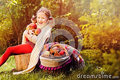 Happy child girl harvesting apples in autumn garden. Stock Photo