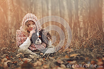 Happy child girl with her spaniel dog on cozy warm autumn walk Stock Photo