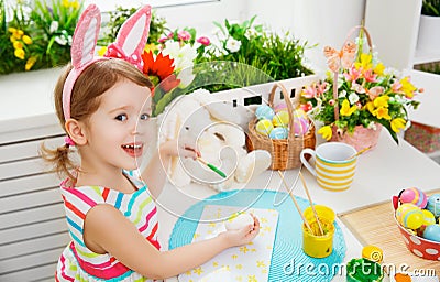 Happy child girl paints eggs for Easter Stock Photo