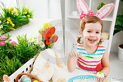 Happy child girl paints eggs for Easter Stock Photo