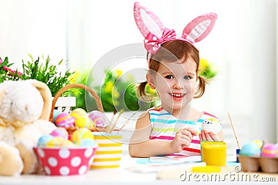 Happy child girl paints eggs for Easter Stock Photo