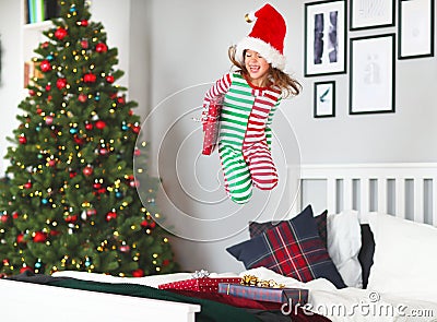 Happy child in pajamas with gifts jumping in bed on christmas m Stock Photo