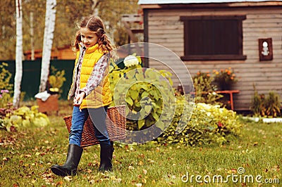 Happy child girl playing little gardener in autumn and picking leaves into basket Stock Photo