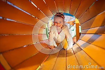 Happy child girl playing in tunnel on playground Stock Photo