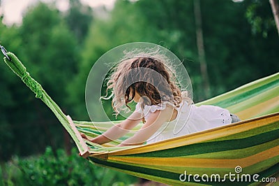 Happy child girl relaxing in hammock on summer camp in forest. Outdoor seasonal activities Stock Photo