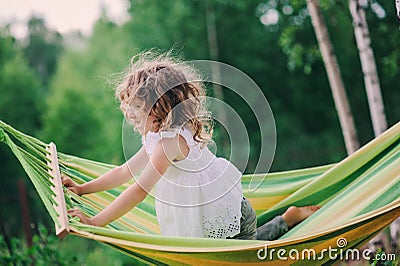 Happy child girl relaxing in hammock on summer camp in forest. Outdoor seasonal activities Stock Photo