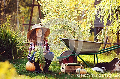 Happy child girl with spaniel dog playing little farmer in autumn garden Stock Photo