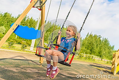 Happy child girl on swing on warm and sunny day outdoors. Little kid playing on nature walk in playground in park, cute blond girl Stock Photo