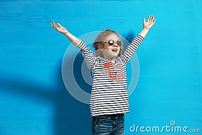 Happy child girl tourist in pink sunglasses at the blue wall. Travel and adventure concept Stock Photo