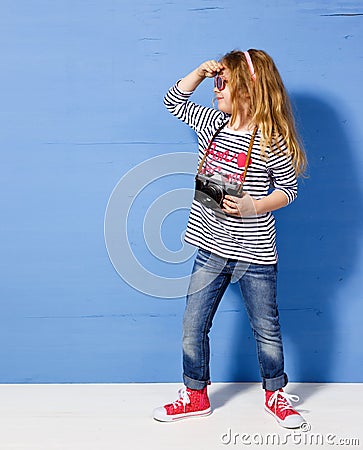 Happy child girl tourist with retro camera at the blue wall Stock Photo