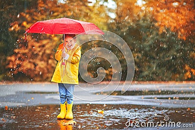Happy child girl with an umbrella and rubber boots in puddle on Stock Photo