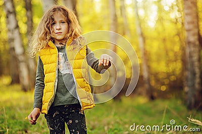 Happy child girl in yellow vest walking in summer sunny forest Stock Photo