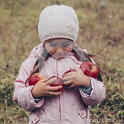 Happy child holding red apples in his hands. Harvest Funny kid outdoors in autumn park Stock Photo