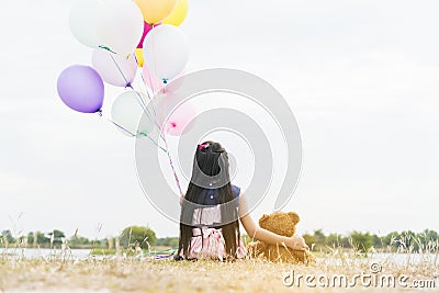 Happy Child hug teddy bear hold air balloon in green park playground. Teddy bear best friend for little kids cute girl. Autism Stock Photo