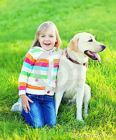 Happy child with labrador retriever dog on grass Stock Photo