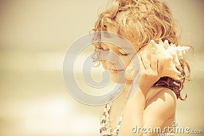 Happy child listen to seashell at the beach Stock Photo