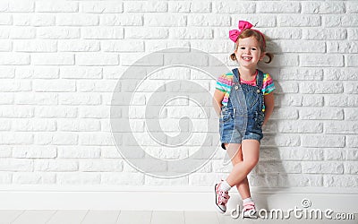 Happy child little girl laughing at blank brick wall Stock Photo