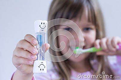 Happy Child measures time while brushes her teeth. Healthy habits, dentalcare concept. Close up Stock Photo