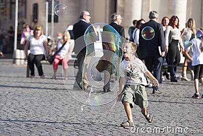 Happy child running towards a soap bubble Editorial Stock Photo