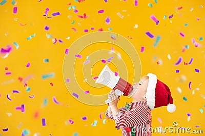 Happy child wearing Santa Claus costume speaking by megaphone Stock Photo