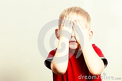 Happy childhood. Blond boy child kid covering face with hands Stock Photo