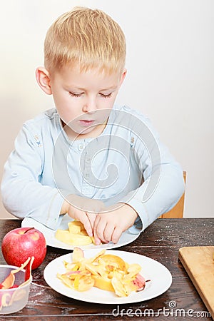 Happy childhood. Boy child kid eating peeled apple fruit. At home. Stock Photo