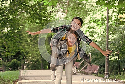 Happy childhood friends have fun piggybacking in park on summer day, holidays Stock Photo
