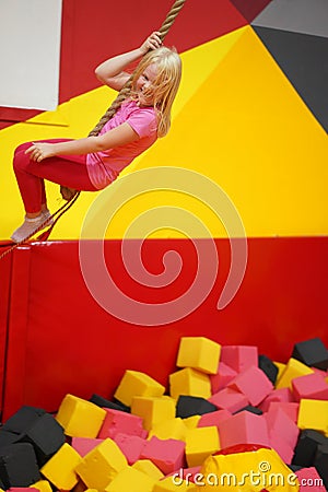 Happy childhood of a modern child in the city - girl in an amusement park riding a rope Stock Photo