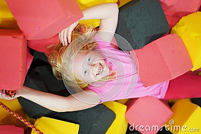 Happy childhood of a modern child in the city - the girl lies in soft cubes in an amusement park Stock Photo