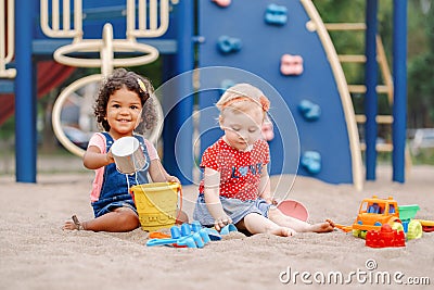 Caucasian and hispanic latin babies children sitting in sandbox playing Stock Photo