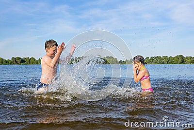 Happy children on the beach play in the water on a sunny day. Lifestyle Stock Photo