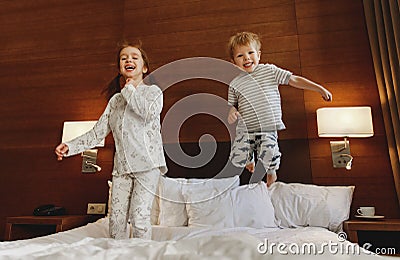 Happy children brother and sister jump on bed in bedroom Stock Photo