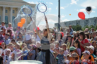 Happy children catch soap bubbles on the street in the city of T Editorial Stock Photo