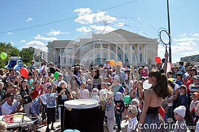 Happy children catch soap bubbles on the street in the city of T Editorial Stock Photo