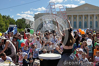 Happy children catch soap bubbles on the street in the city of T Editorial Stock Photo