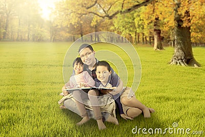 Happy children and father sitting at autumn park Stock Photo