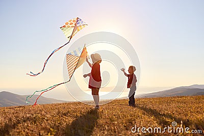 Happy children girl and boy launches a kite at sunset outdoors Stock Photo