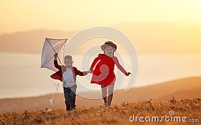 Happy children girl and boy launches a kite at sunset outdoors Stock Photo