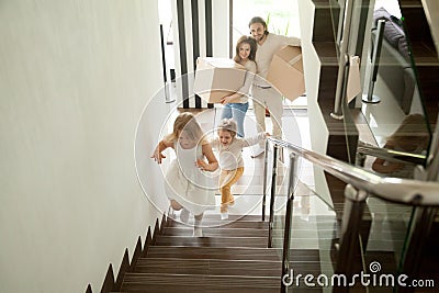 Happy children going upstairs, family with boxes moving in house Stock Photo