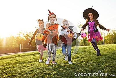 Happy children in Halloween costumes running on lawn Stock Photo