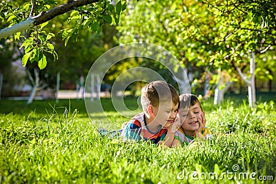 Happy children having fun outdoors. Kids playing in summer park. Little boy and his brother laying on green fresh grass holiday ca Stock Photo