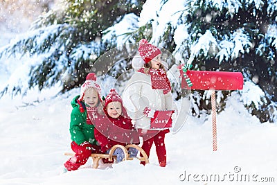 Children with letter to Santa at Christmas mail box in snow Stock Photo